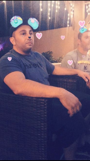 Two men sitting outdoors with playful Snapchat filters of blue ears and hearts.