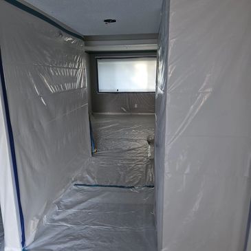 Room covered in plastic sheets for protection during renovation.