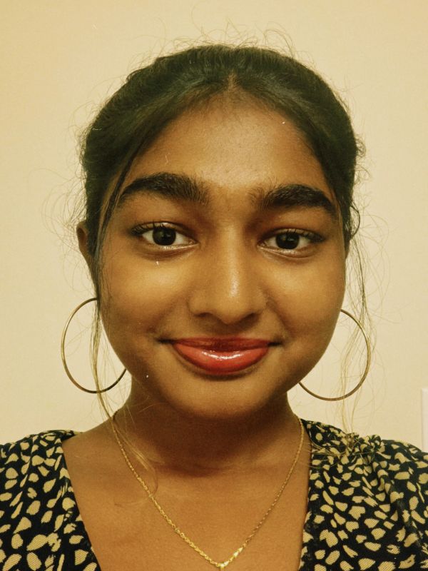 Young woman smiling with hoop earrings and a necklace.