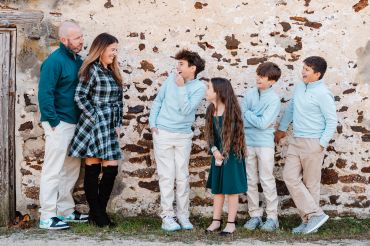 A family of six having fun outdoors against a stone wall.
