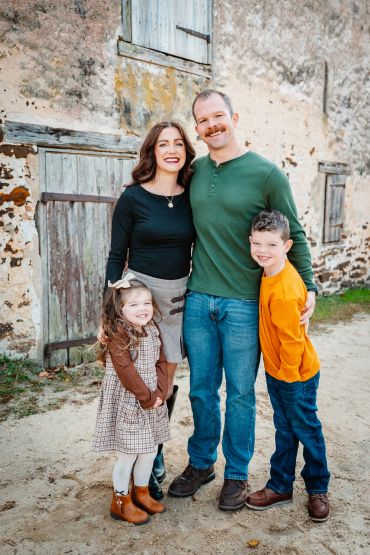 Happy family posing outdoors in front of an old building.