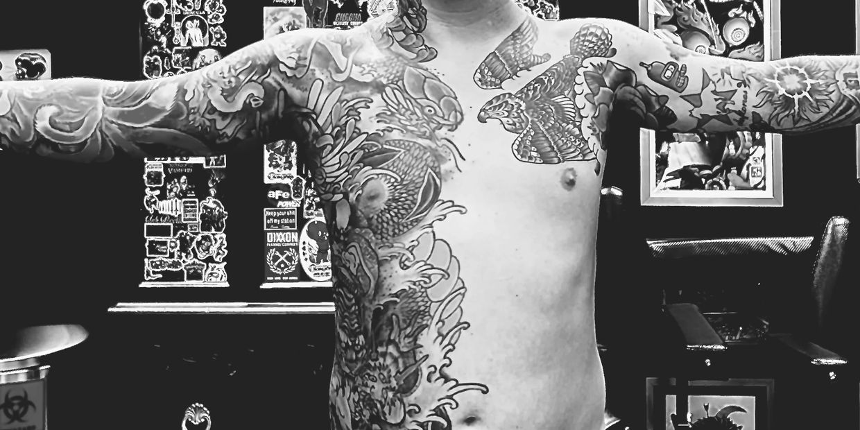 Man showing extensive tattoos on chest and arms.