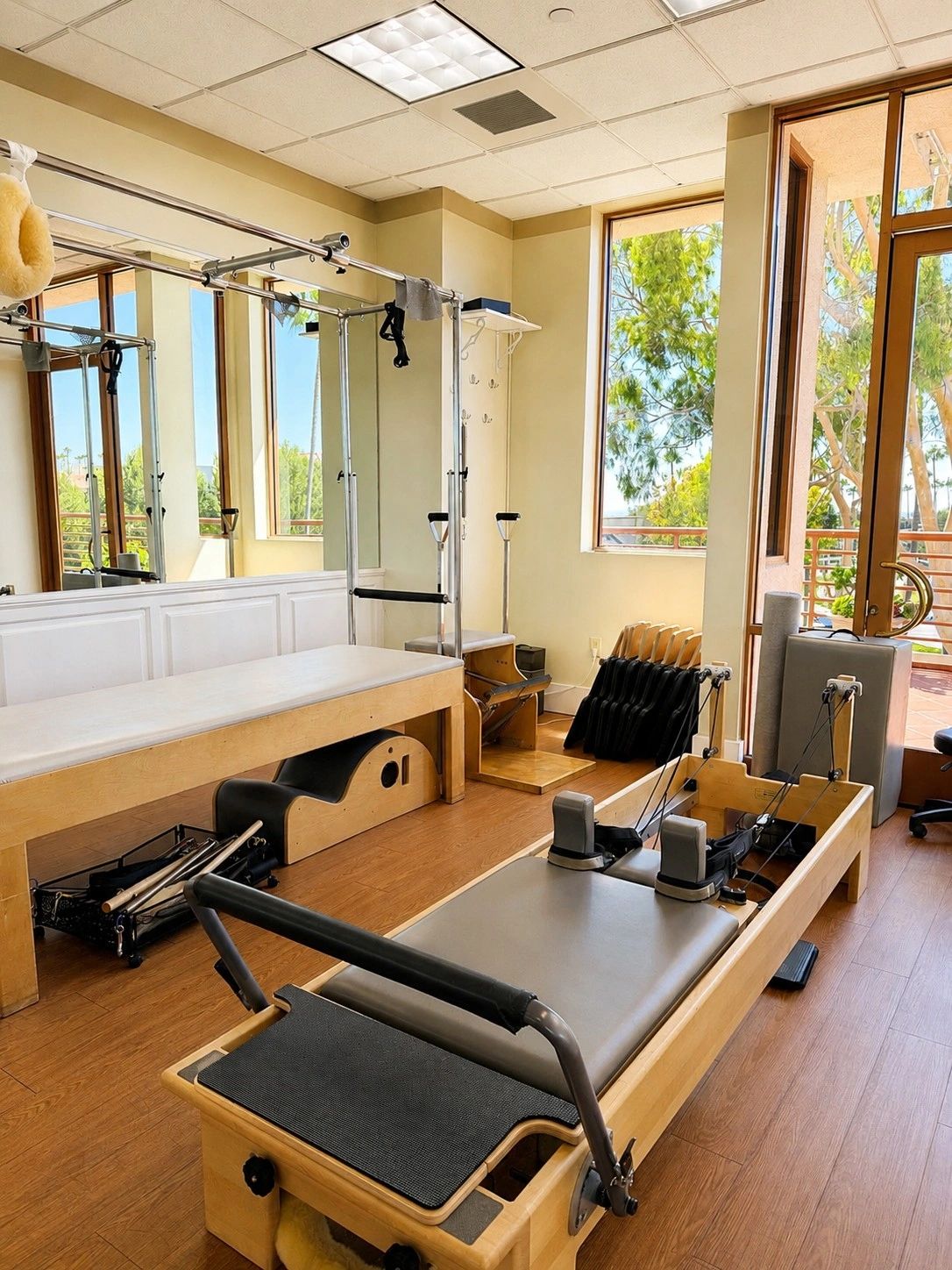 A bright Pilates studio with reformer and chair equipment.