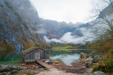 Bootshaus am türkisfarbenen Obersee wird von den Berchtesgadener Alpen im Herbst umrahmt