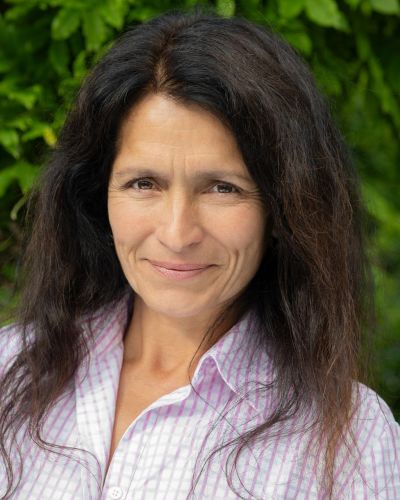 Smiling woman with long dark hair outdoors.