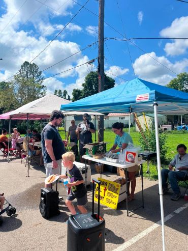 Community event with people under tents on a sunny day.