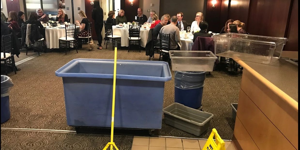 Cleaning supplies in front of a dining area with people seated at tables.