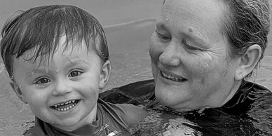 A happy child and an adult smiling together in water.
