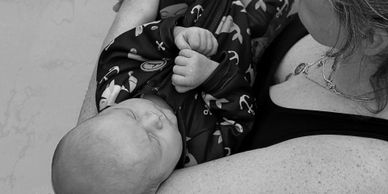 A baby peacefully sleeping in a woman's arms, captured in black and white.