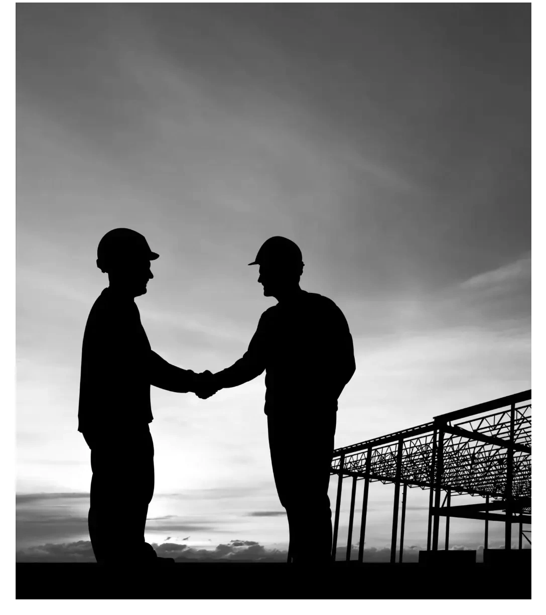 Construction workers sealing a deal with a handshake at a job site.