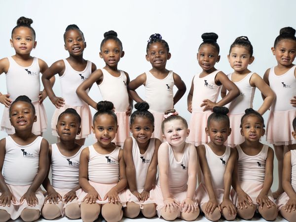 Young ballet dancers in peach leotards smiling.