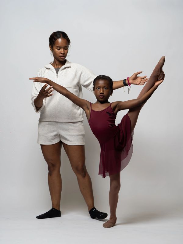 Ballet teacher instructing young dancer.
