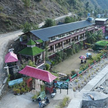 A scenic hillside resort with a garden and riverbed nearby.