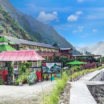 A colorful resort nestled in a lush mountainous valley under a bright blue sky.