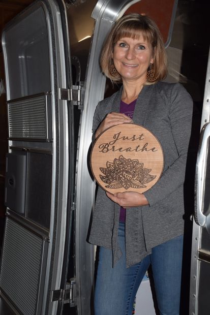 Gypsy Crafter, posing with a handcrafted home decor piece in her Airstream RV. 