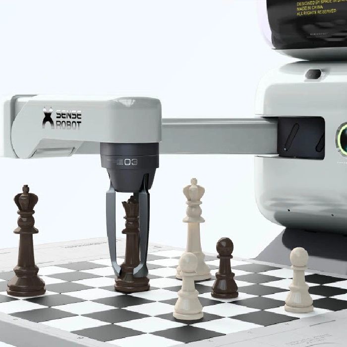 A robotic arm playing chess by moving a black king piece on the board.