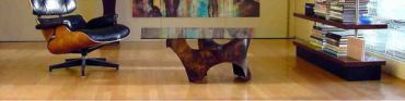 Modern glass coffee table with a wooden base and lounge chair.