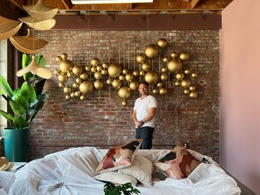 Man standing in front of decorative wall art and plants.