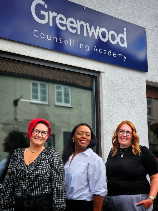 Three women smiling outside Greenwood Counselling Academy.