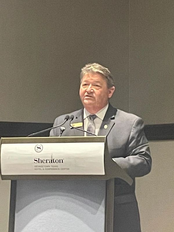 Man speaking at Sheraton Georgetown podium.