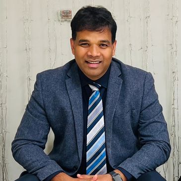 Man in blue suit and striped tie smiling at the camera.