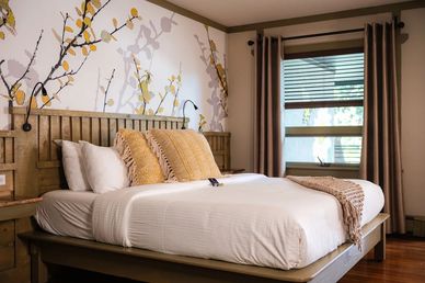 Cozy bedroom with floral wallpaper and soft pillows.