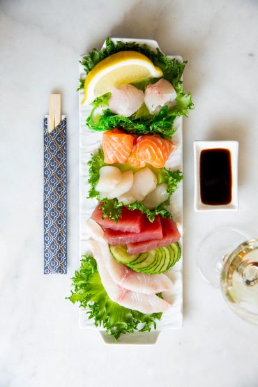 Assorted sashimi platter with soy sauce and a lemon wedge.