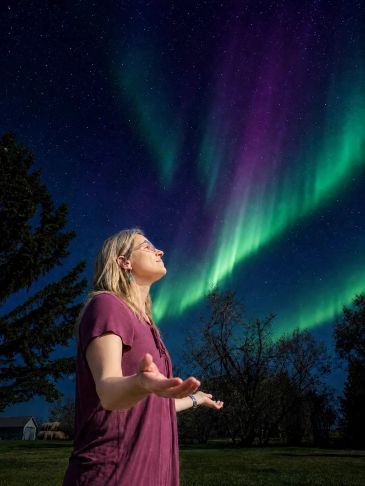 Woman enjoying the vibrant northern lights at night.