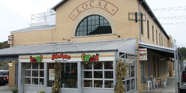 Exterior of a local fresh market with a rustic brick building and glass windows.