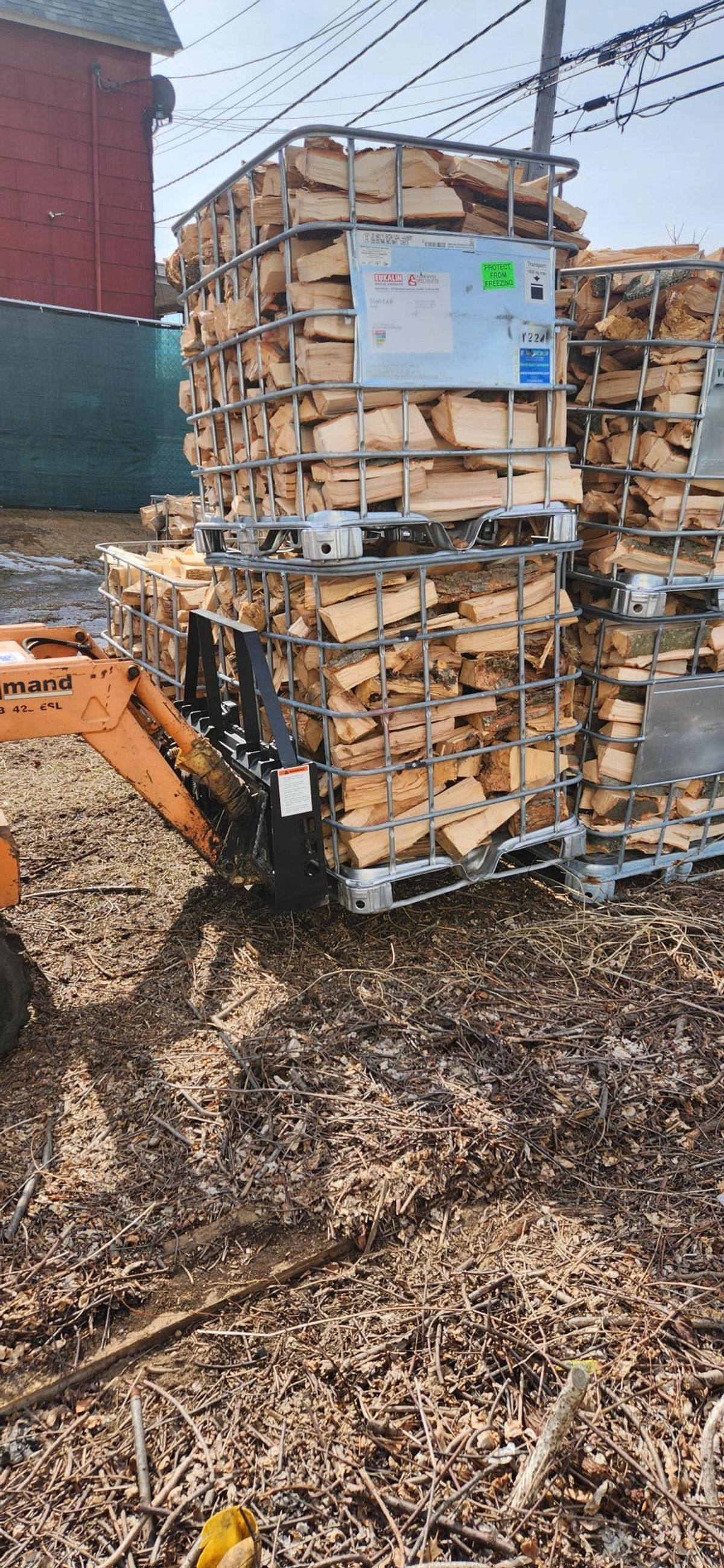 Split hardwood seasoning inside an IBC tote cage, open on all sides for airflow