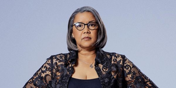 Confident woman with gray hair wearing glasses and a black lace top.