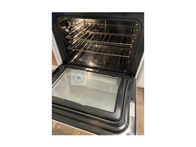 Open modern kitchen oven with clean interior and glass door.