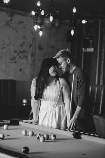Couple sharing a tender moment by a pool table in a cozy setting.