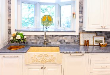 Bright kitchen sink area with decorative bowl and flowers.