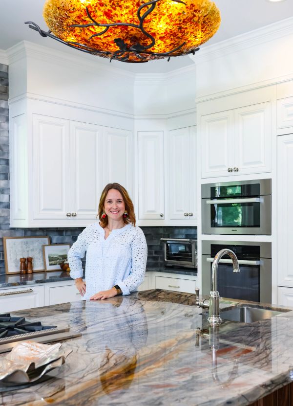 Smiling woman in white shirt standing in modern kitchen.