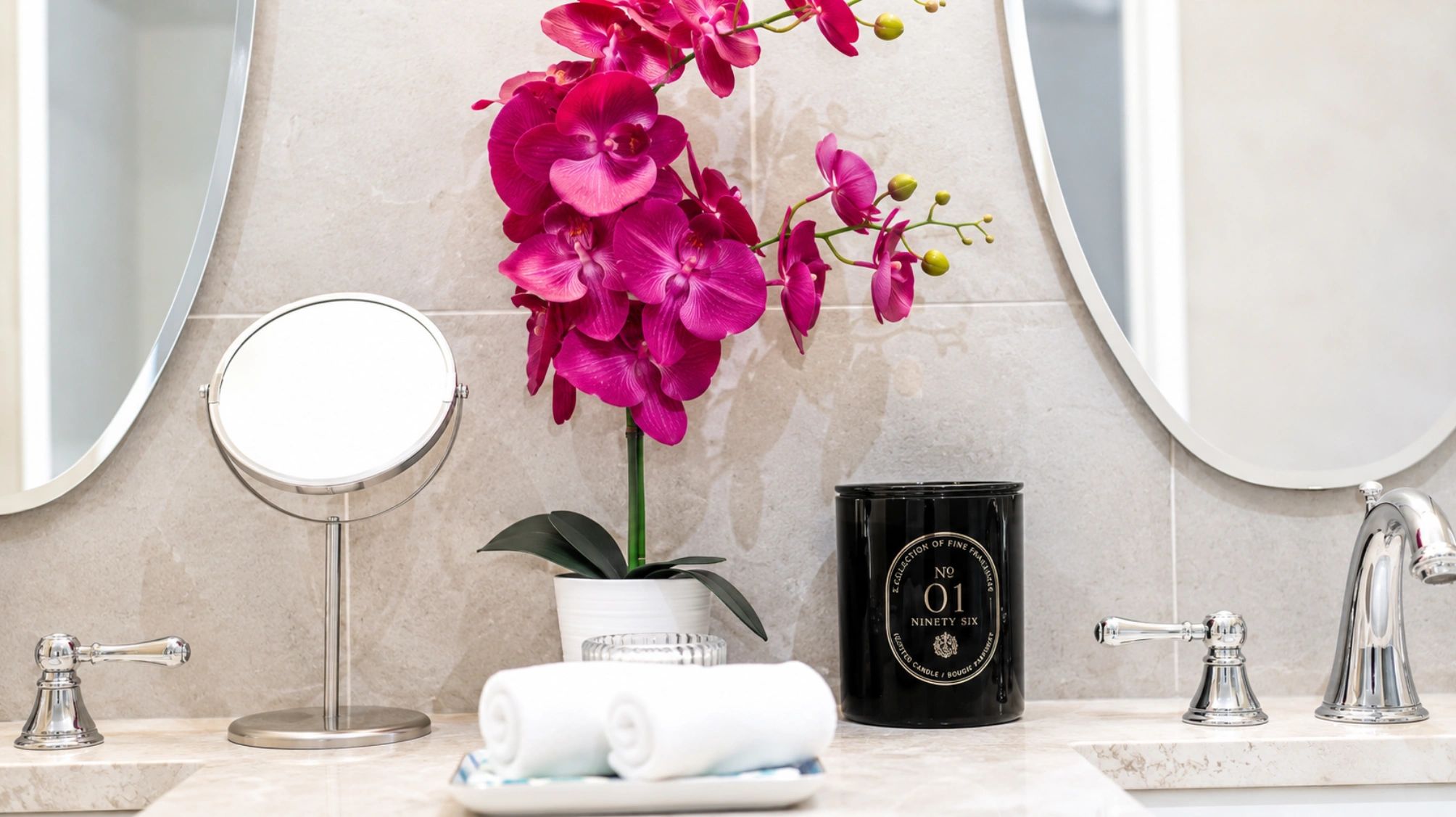 Elegant bathroom setup with vibrant orchids and rolled towels.