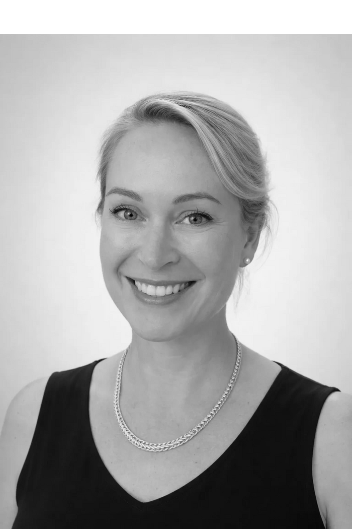 Kylie Aitken Smiling woman with blonde hair, wearing a navy top and gold necklace.