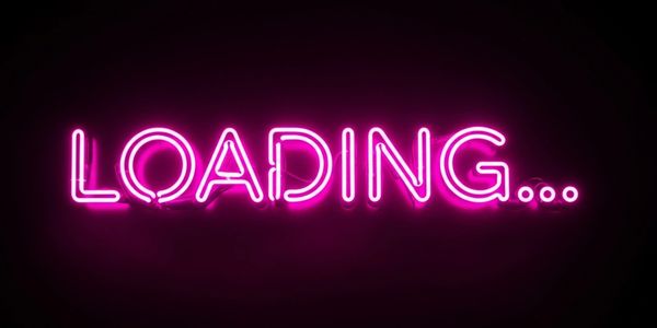 Bright pink neon sign spelling 'LOADING...' on black background.