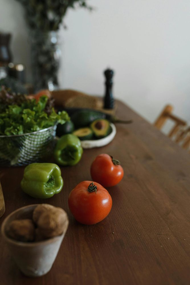 Fresh vegetables and walnuts on a wooden table in a cozy kitchen.