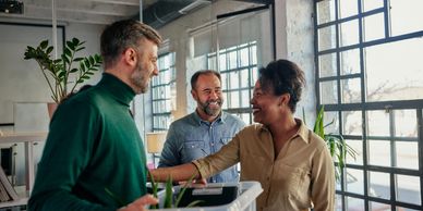 Three coworkers happily discuss near the office window.