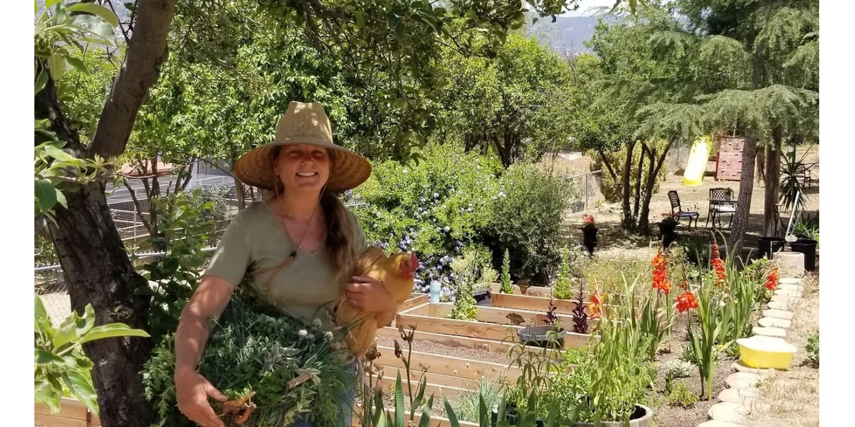 Annalisa harvesting herbs with Goldielocks, the chicken.