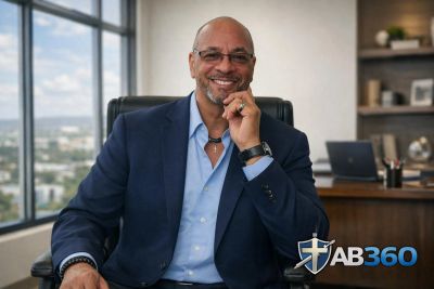 A confident man in a suit sitting in an office with a city view.