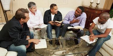 A group of five men having a Bible study at home.
