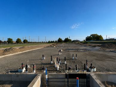 Construction site with plumbing pipes on foundation.