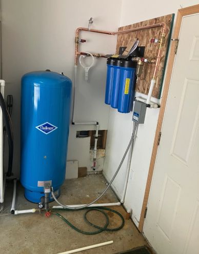 Indoor water filtration system with blue tanks and pipes.