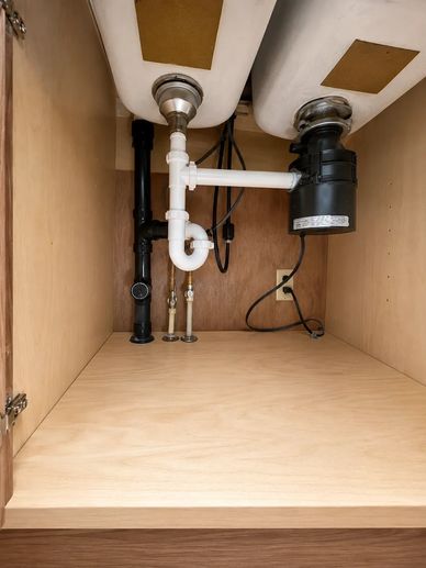 Plumbing and garbage disposal under kitchen sink.