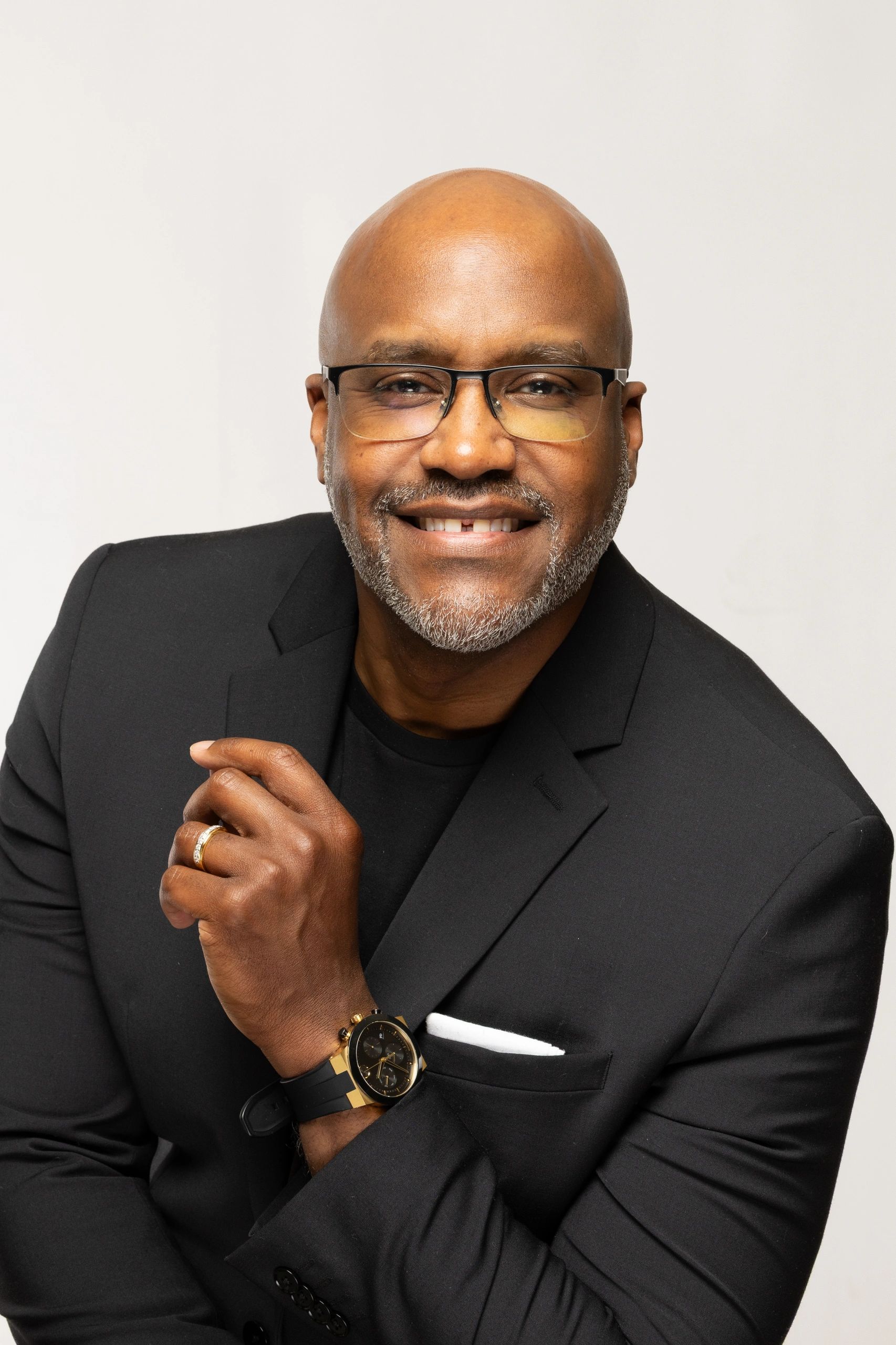 Smiling man in glasses and black suit jacket posing confidently.