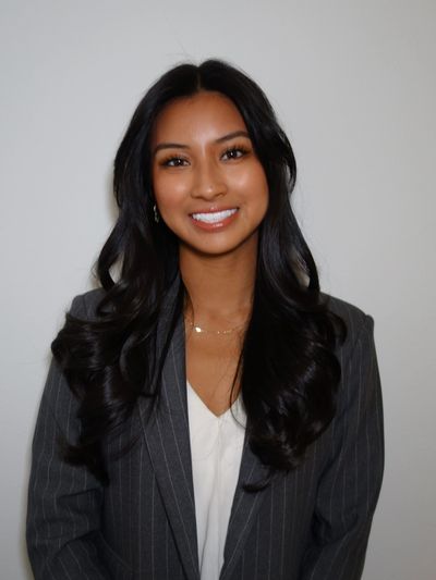 Smiling woman with long black hair in a gray pinstripe blazer.