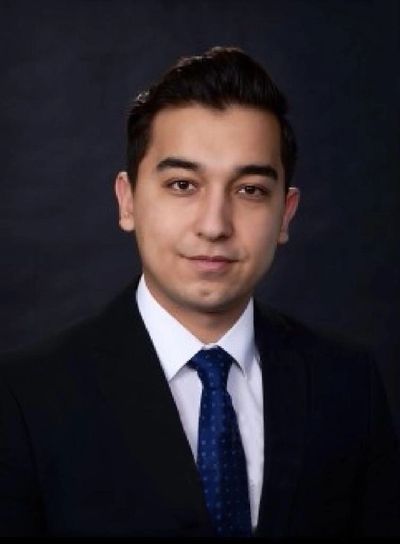 Professional young man in suit and tie against dark background.