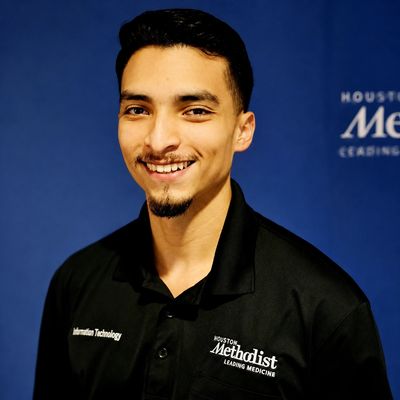 Young man smiling, wearing a Houston Methodist polo shirt.